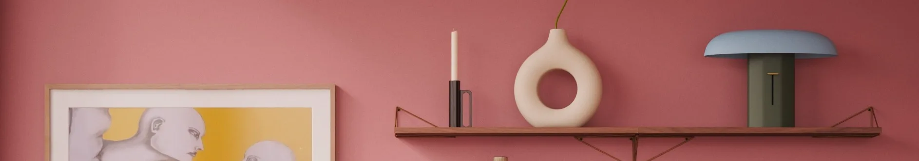 Rosa vegg, trehylle: hvitt lys, krem smultringvase med grønn stilk, blå og grønn lampe. Innrammet kunstverk til venstre.