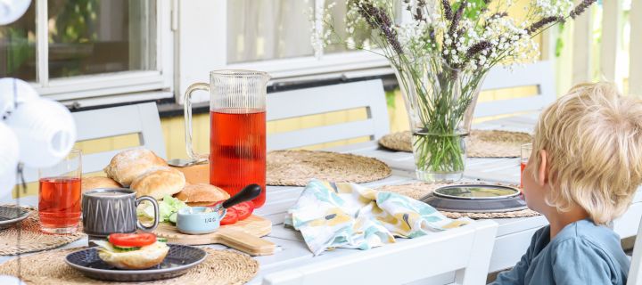 Bilde som viser en liten gutt sittende ved et dekket frokostbord med nybakte kaldhevede rundstykker.