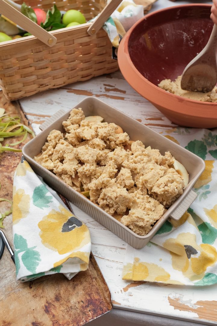 Bilde som viser Flora ildfast form fra Sagaform, en beige form med håndtak, med en ubakt eplekake i.