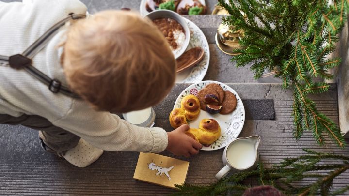 Her ser du et barn som strekker seg etter en lussekatt på en tallerken fra Rörstrands svenske Grace Winter-kolleksjon.