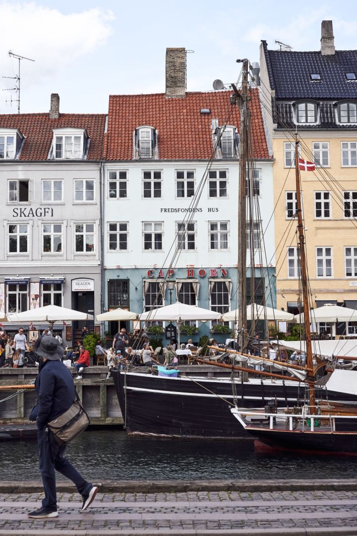 Havnen i Nyhavn er et must på enhver bytur i København. Her ser du noen gå forbi de fargerike bygningene i havna.