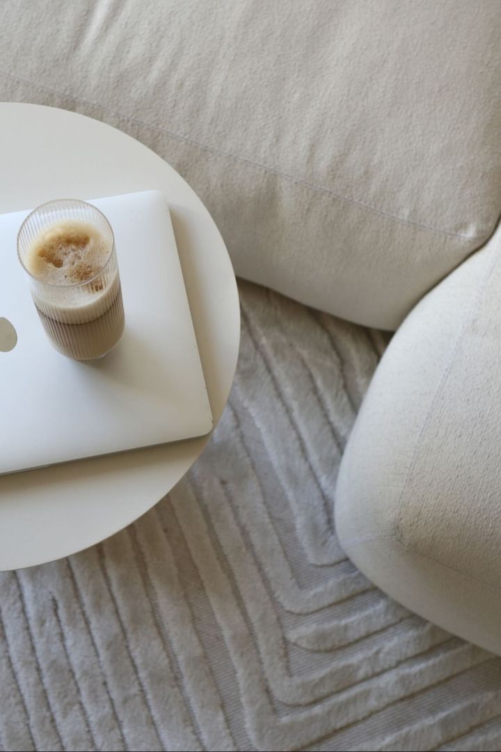 Her kan du se en perfekt tilberedt latte macchiato i et longdrinkglass fra Ripple-kolleksjonen til Ferm Living, som står på et salongbord ved siden av en beige-farget sofa i @ellesklingens hjem.