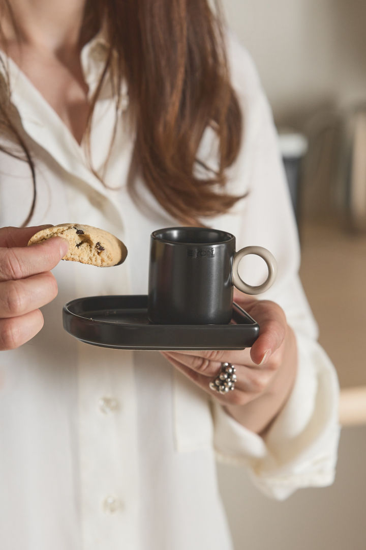 Her kan du se en kvinne som holder Niki espressokoppen fra Byon i den ene hånden og en biscotti i den andre.