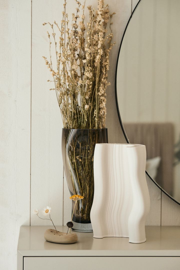 Den 3D-printede Moire-vasen fra ferm LIVING står på en kommode sammen med en vase med tørkede blomster. Strukturerte og taktile materialer blir en stor trend høsten 2024.