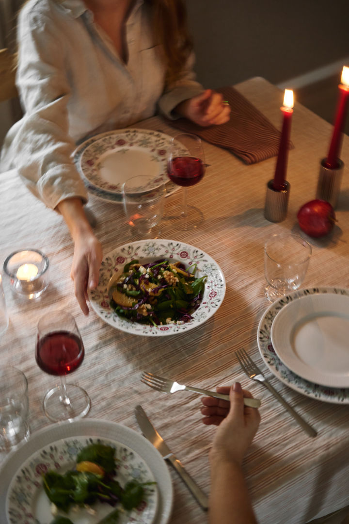 En hånd sender en vintersalat over bordet som en del av en skandinavisk juleborddekking. 