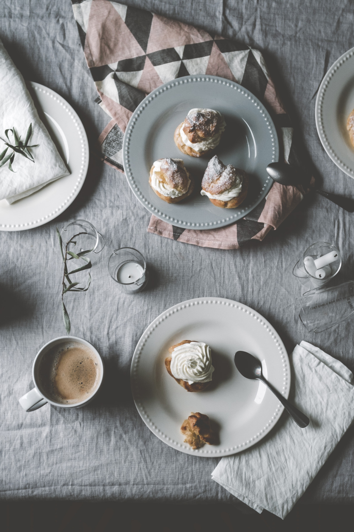 Her ser du @kohlundkimchis Semlor stående på et bord på tallerkener i forskjellige farger fra Dots-kolleksjonen fra Scandi Living, ledsaget av en kopp kaffe.