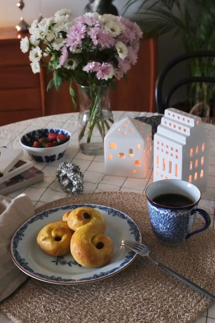 Her ser du et bord med friske blomster og julepynt i form av Urbania-lysestaker fra Kähler og svenske lussekatter på en Ostindia-tallerken fra Rörstrand hjemme hos @_mariano_rivera_4242.