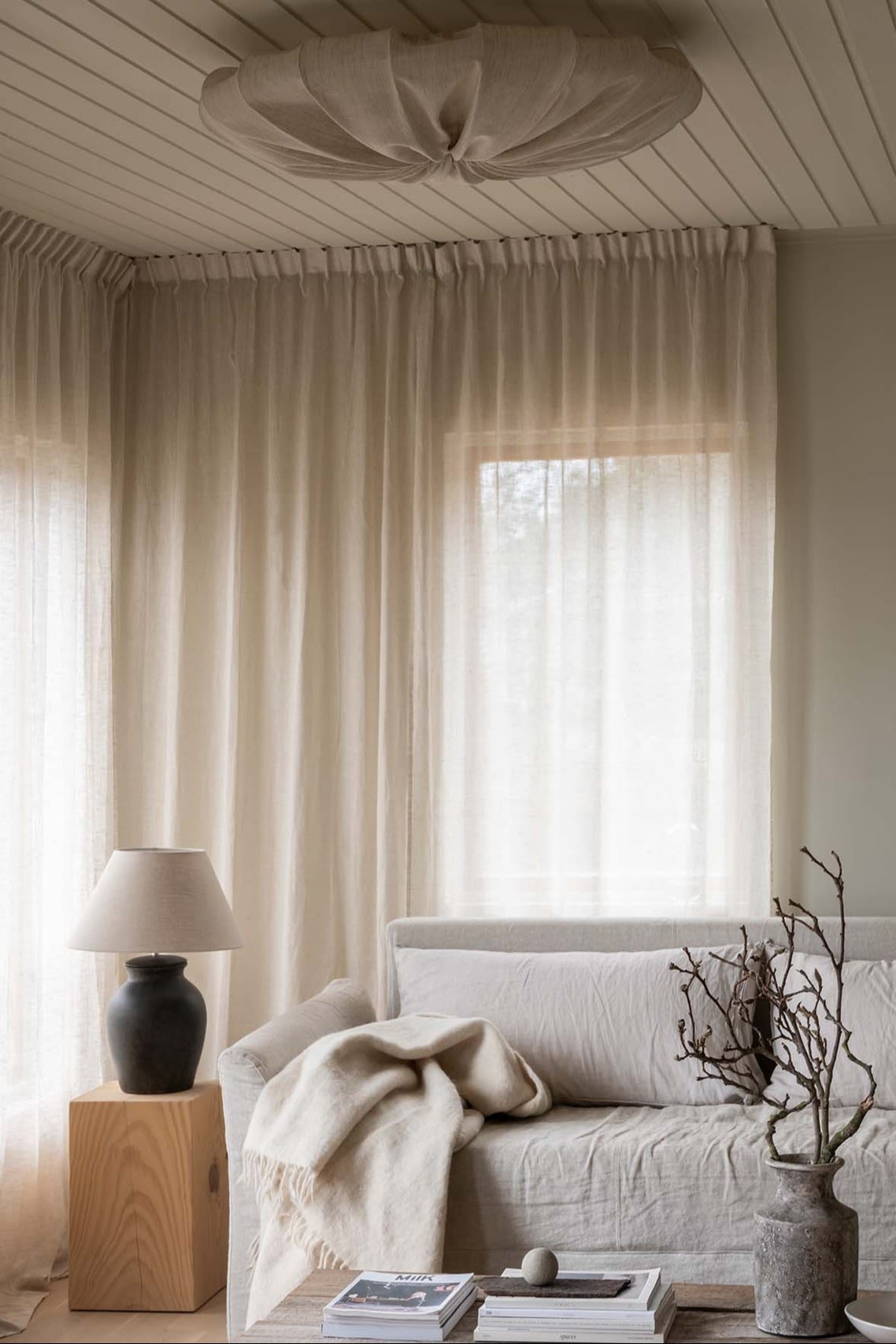 Taklampe stue - her ser du en lys stue med beige sofa og lyse gardiner, Anna plafond i linstoff fra Watt & Veke henger i taket.