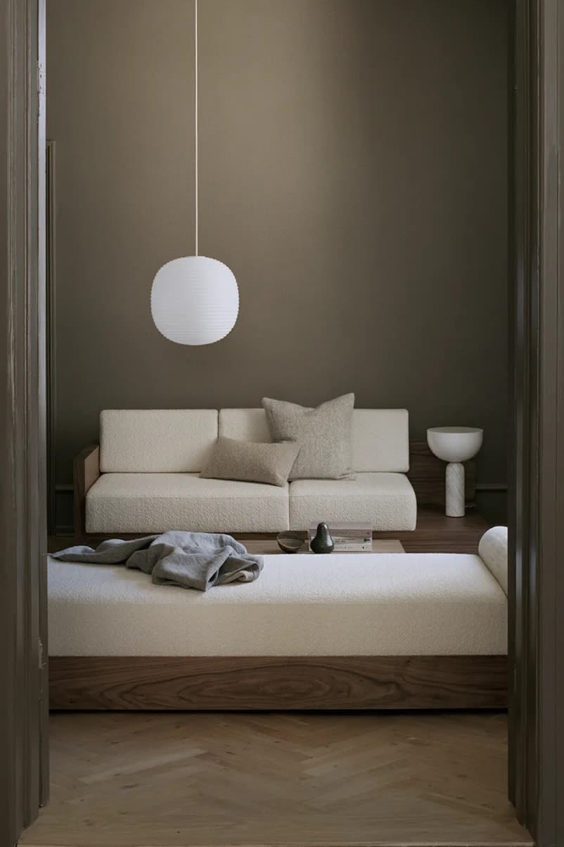 Taklampe stue - bildet viser taklampen Lantern fra New Works, en hvit, oval taklampe her hengende i stua ved siden av en lys sofagruppe.