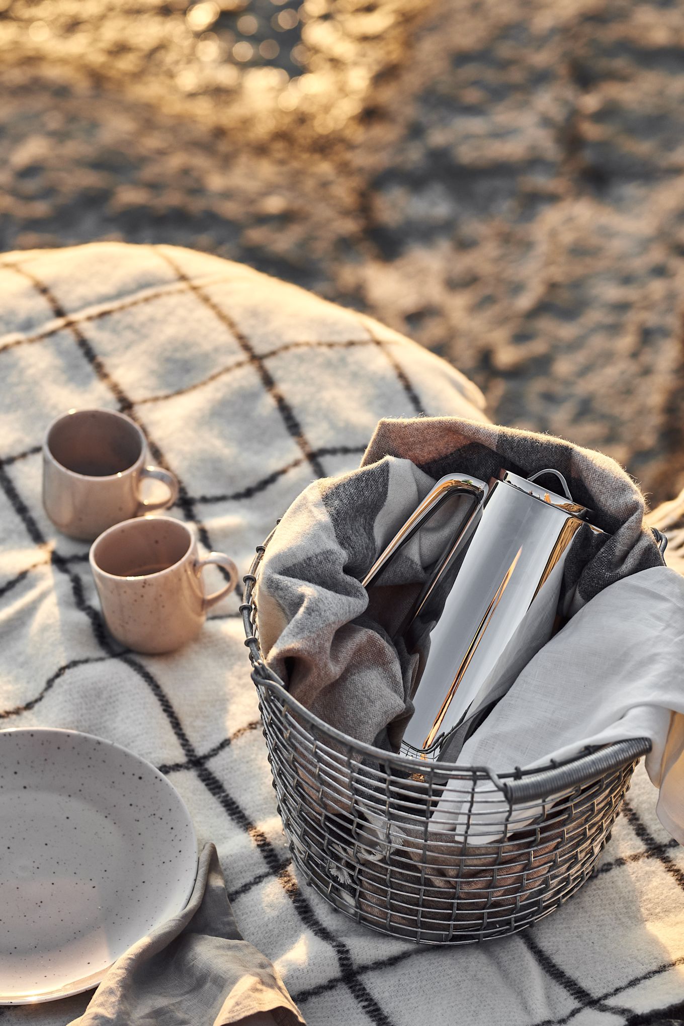 Piknik på stranden med termos klar i stilig Korbo-kurv, prikkede krus på rutete og prikkete servise.